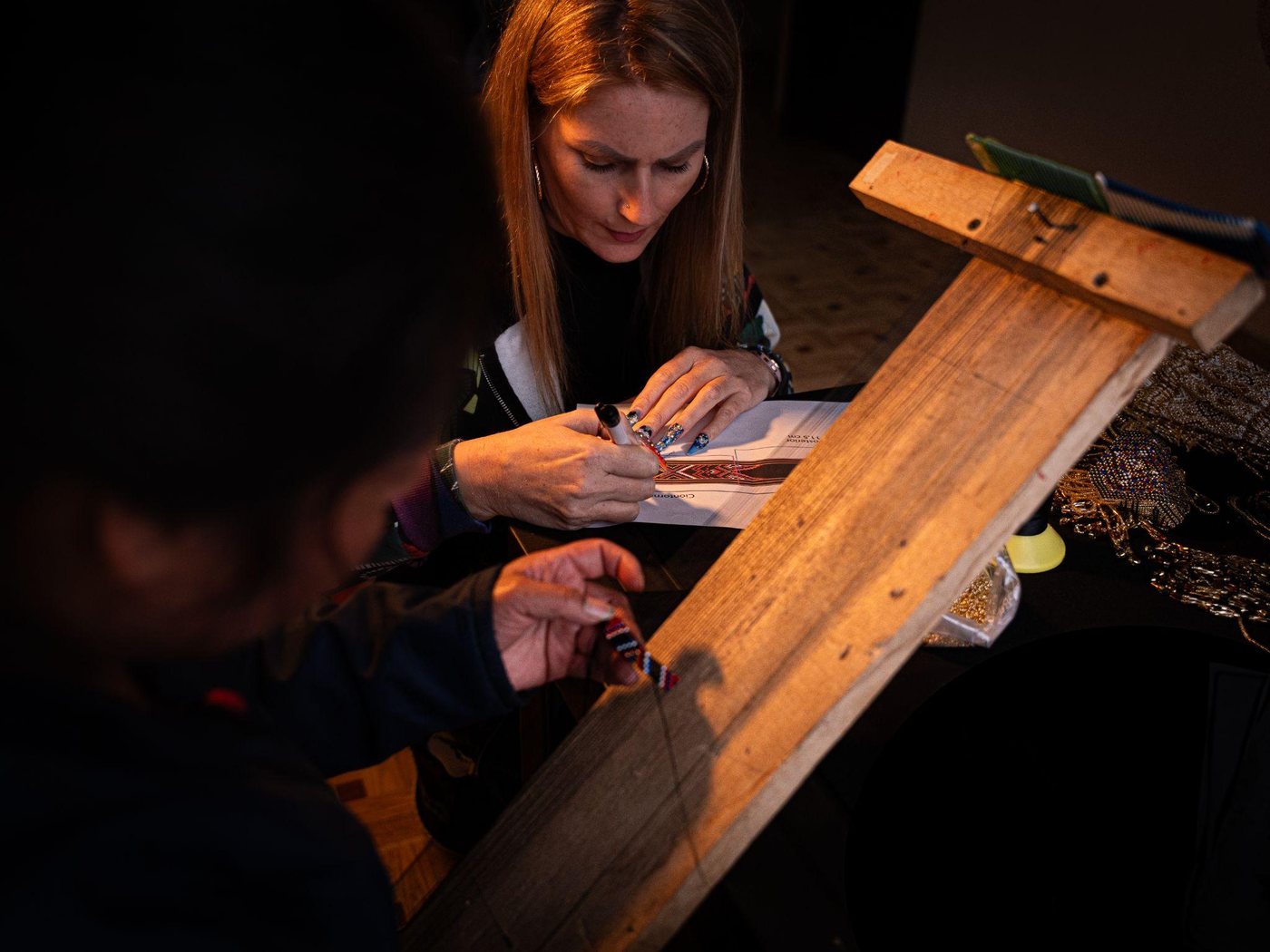 Anika Stevens at a workbench, co-creating a beaded piece with a local artisan